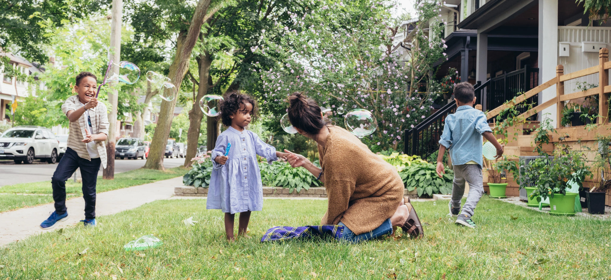 Mother kneeling on front lawn, playing with three children